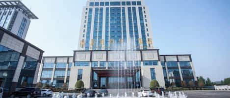 A modern building with a central fountain, large windows, and a clear sky.