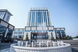 A modern building with a central fountain, large windows, and a clear sky.
