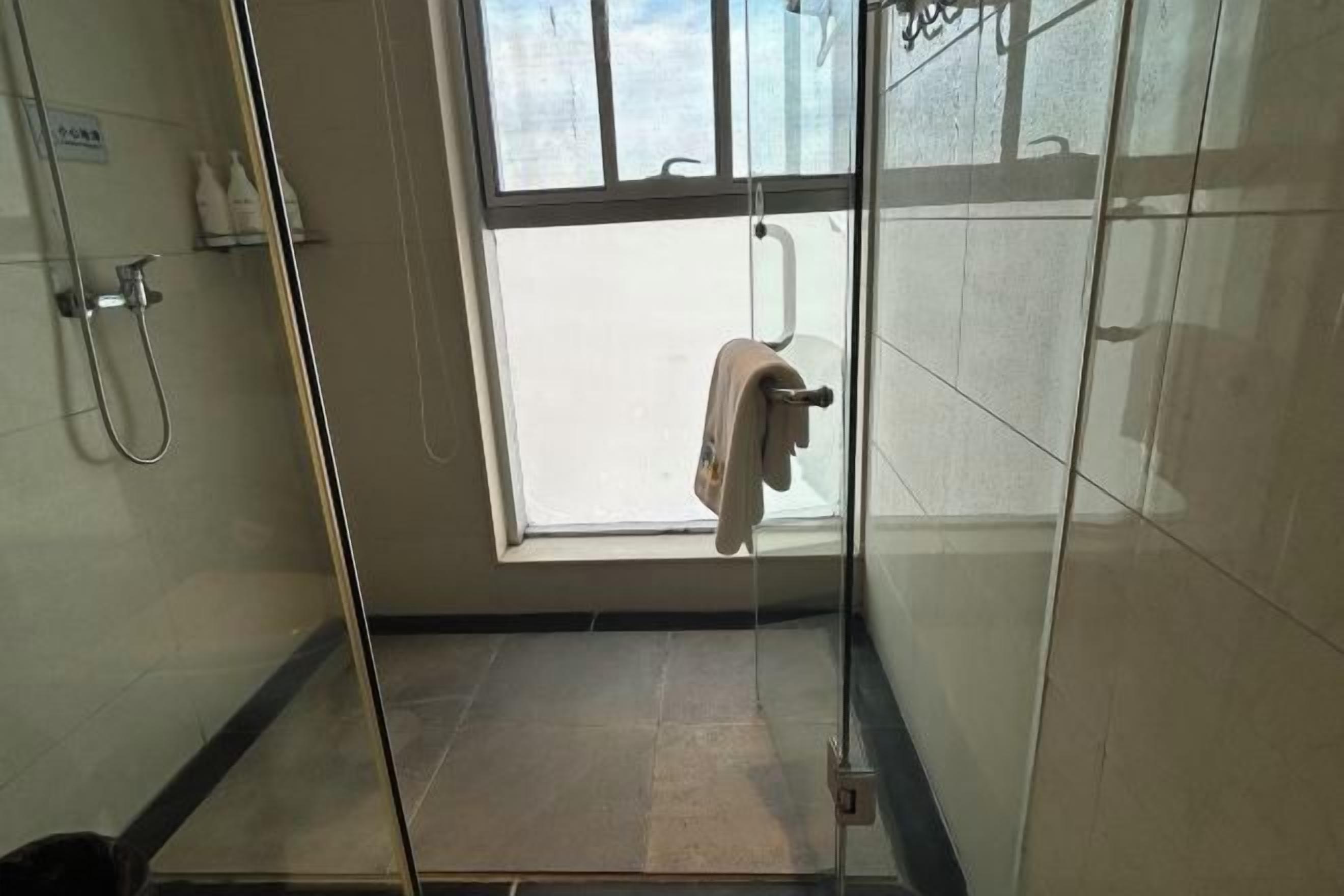A glass-enclosed shower with a towel rack and a window.