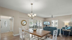 A spacious living area with a wooden dining table, white chairs, a blue sofa, and a ceiling fan. - Island House Beach Resort 12S (Sarasota)