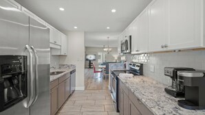 A modern kitchen with stainless steel appliances, white cabinetry, and a granite countertop. - Island House Beach Resort 12S (Sarasota)