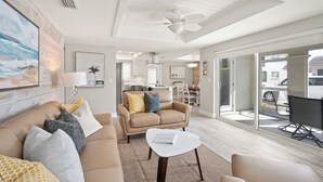 Un salon moderne avec un canapé beige, une table basse blanche et un ventilateur de plafond.