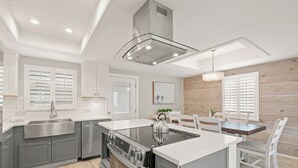 Une cuisine moderne dotée d’un îlot central, d’appareils électroménagers en acier inoxydable et d’un coin repas agrémenté d’éléments en bois.