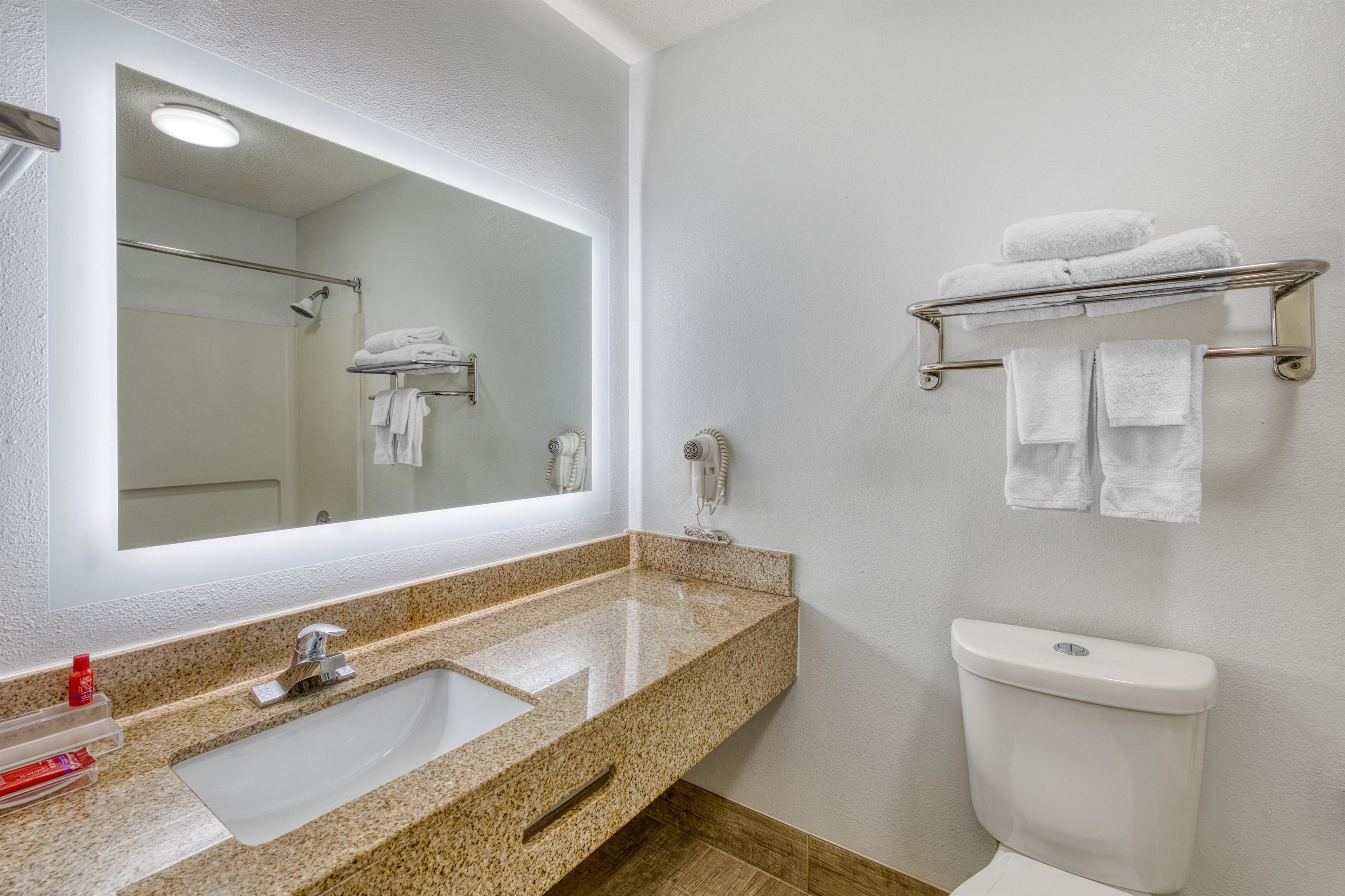 Une salle de bain équipée d’un lavabo, d’un miroir, d’un porte-serviettes et de toilettes.