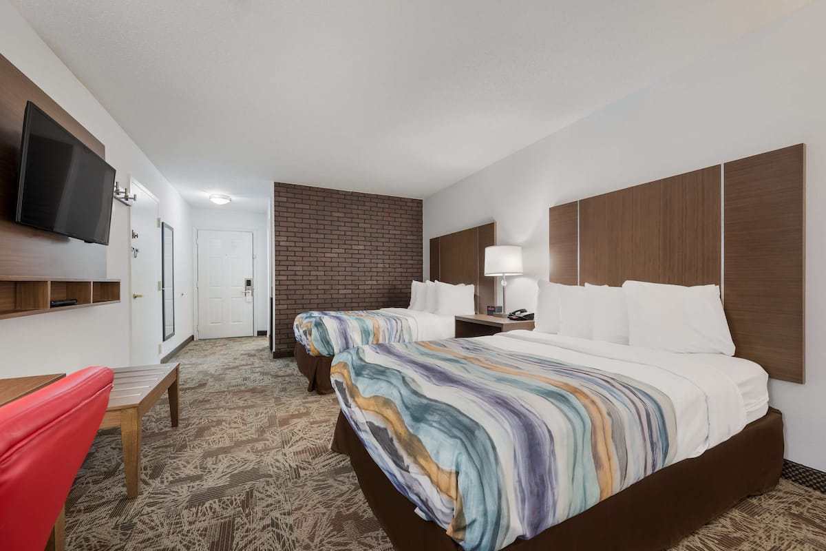 A hotel room with a large bed, a TV mounted on the wall, a desk, and a chair.