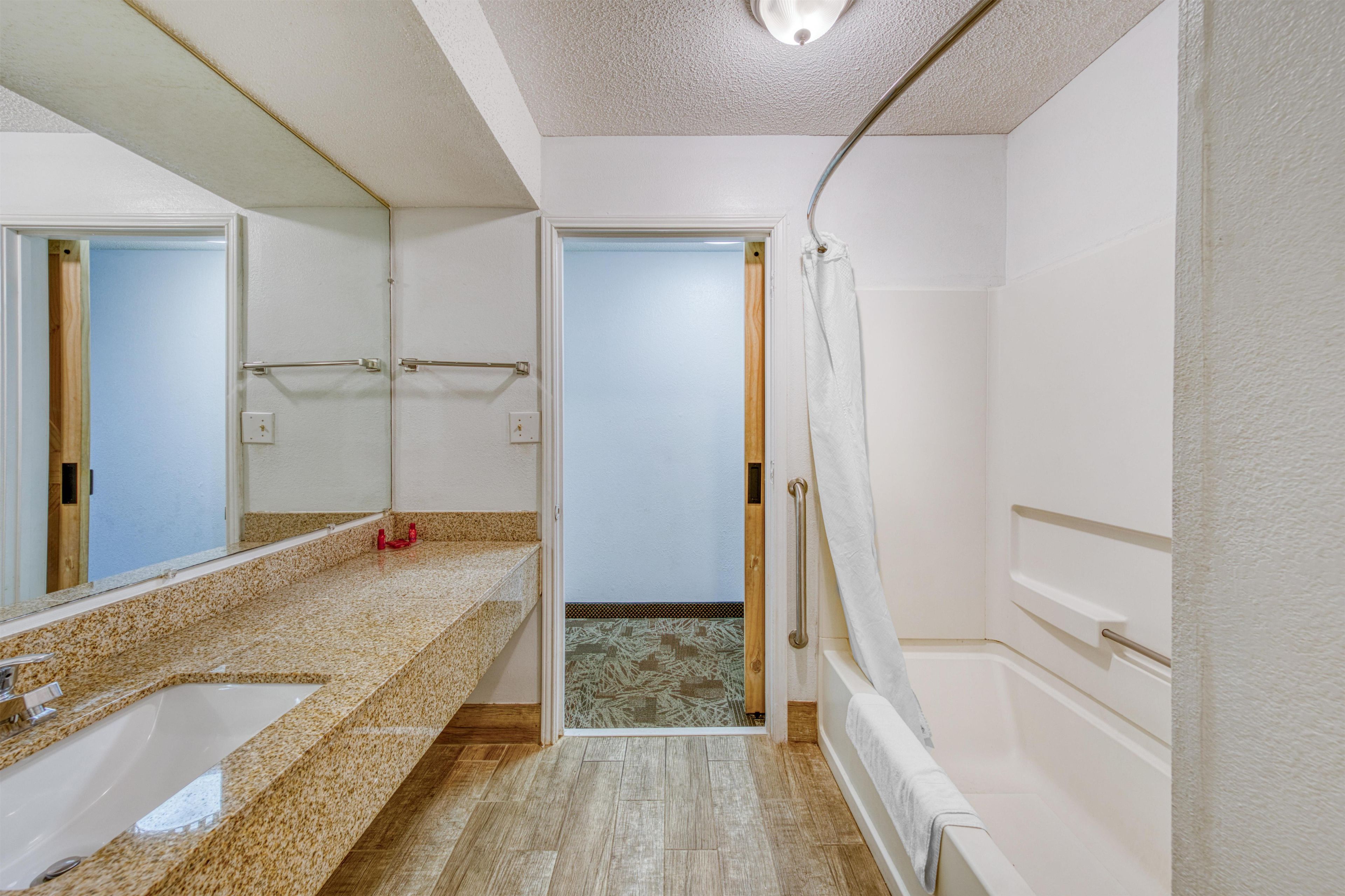 A bathroom with a sink, mirror, towel rack, and shower area.