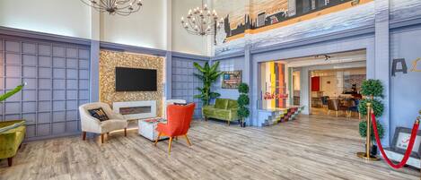 A spacious lobby with a high ceiling, a large chandelier, and a cityscape mural on the wall.