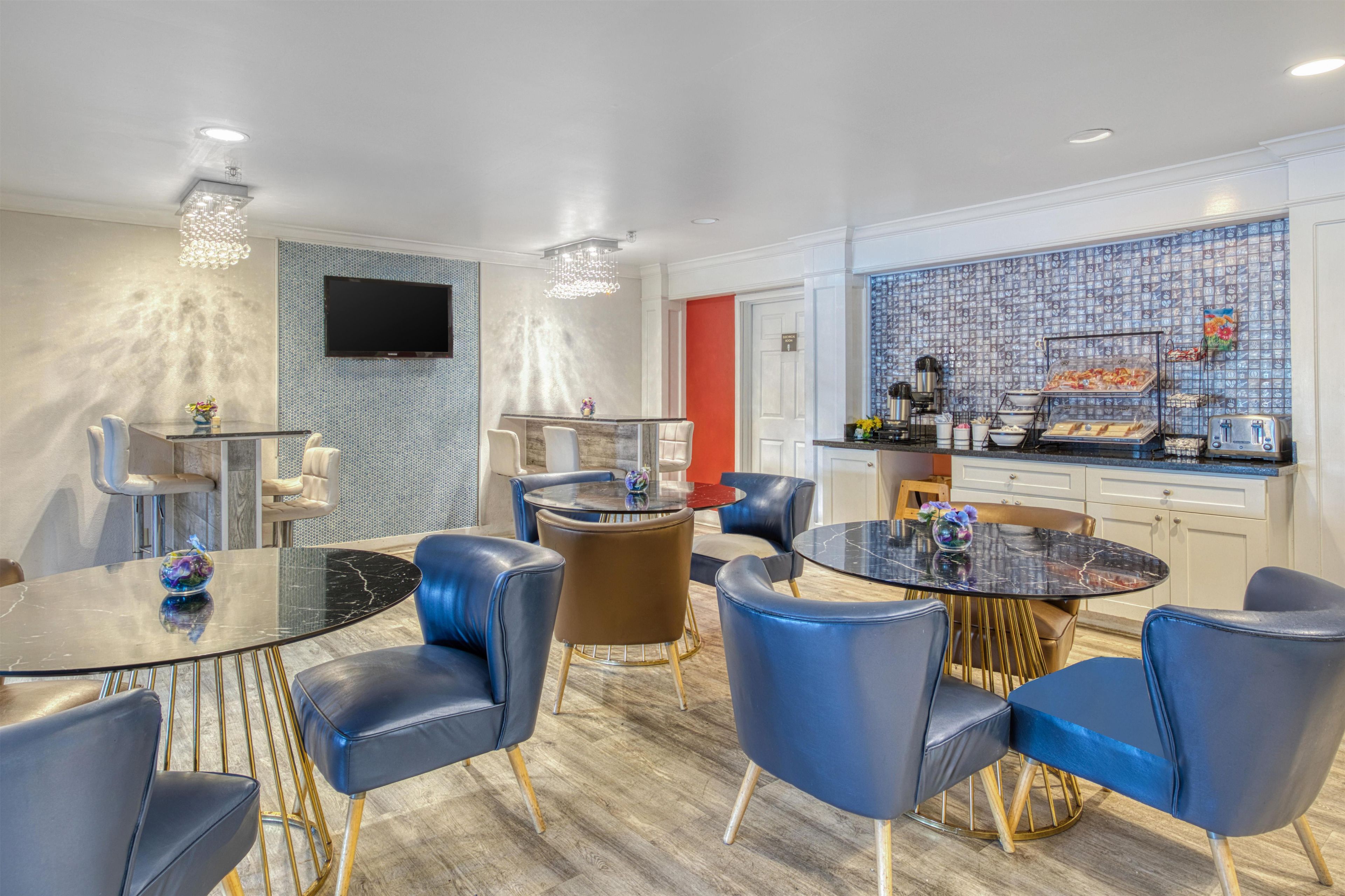 Habitación de hotel moderna con comedor, cocina y televisor montado en la pared.