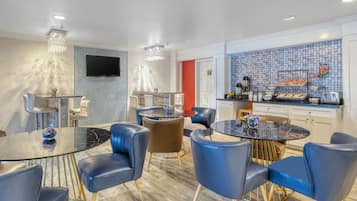 Habitación de hotel moderna con comedor, cocina y televisor montado en la pared.