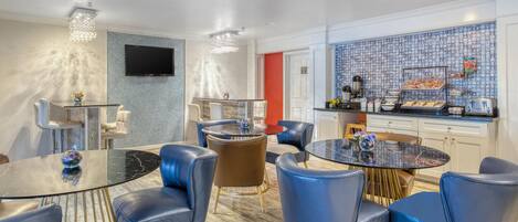Habitación de hotel moderna con comedor, cocina y televisor montado en la pared.