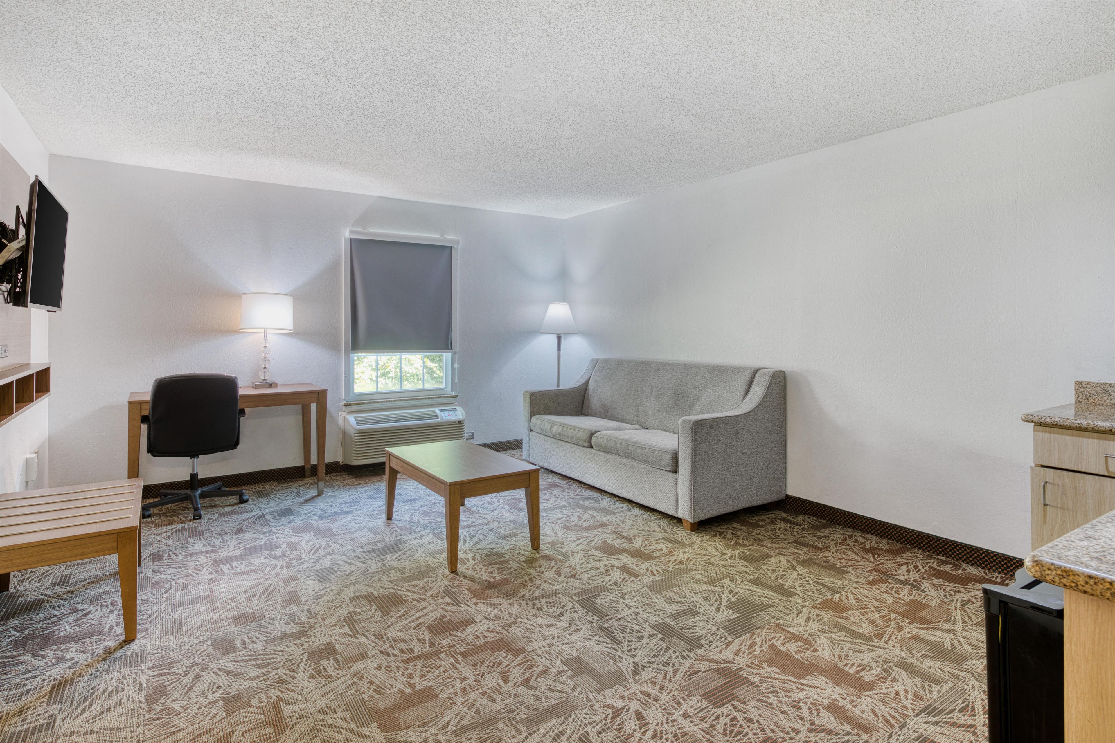 A small, sparsely furnished room with a sofa, a desk, a chair, and a small table.
