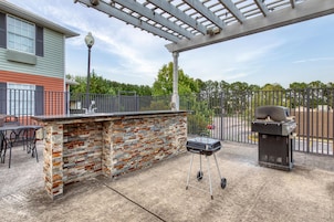 An outdoor patio with a brick bar, a grill, and a pergola.