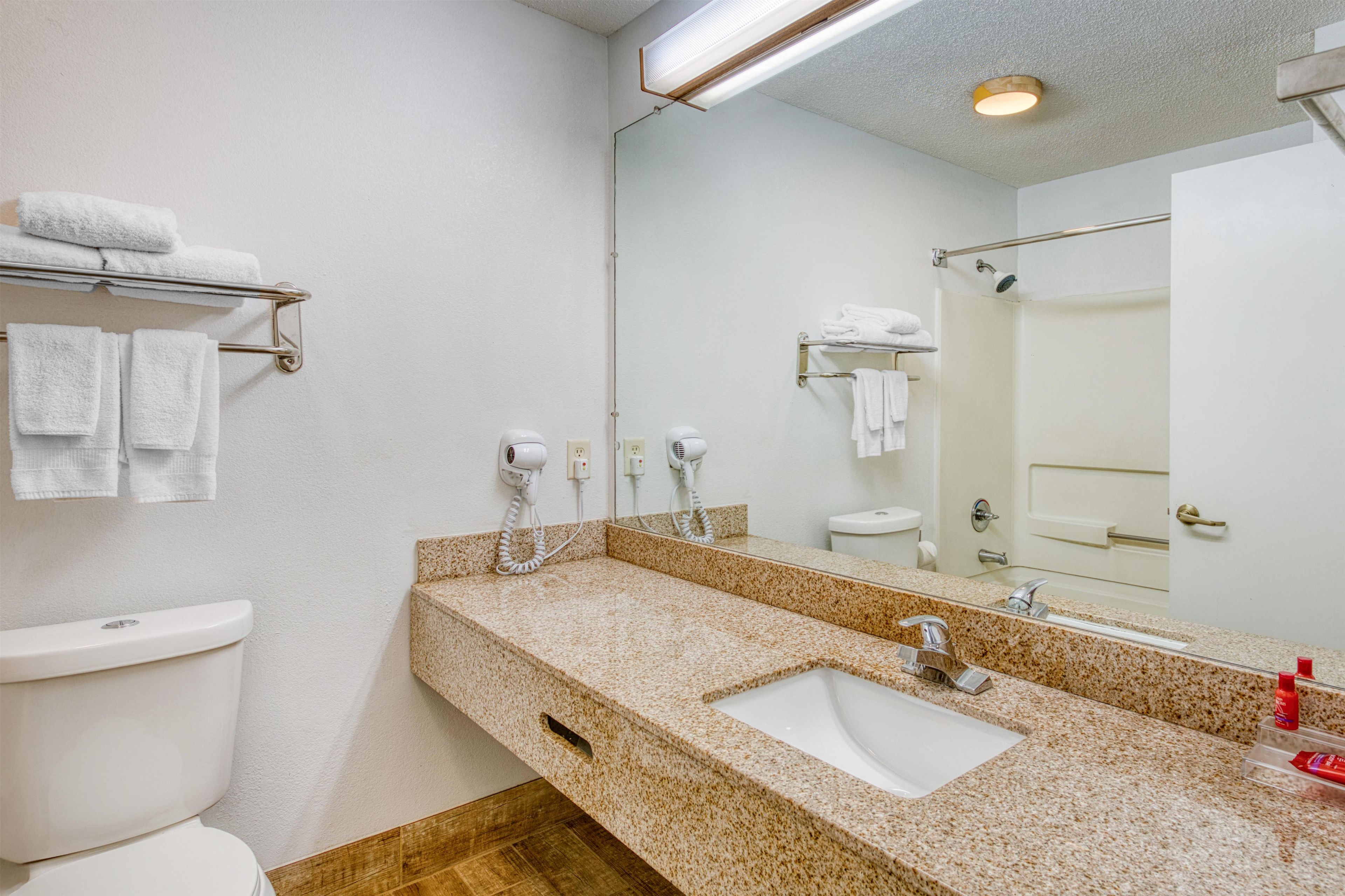 A bathroom with a white toilet, a sink with a mirror, and a towel rack.