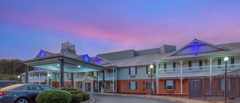 A hotel with a covered entrance, multiple stories, and a parking area.