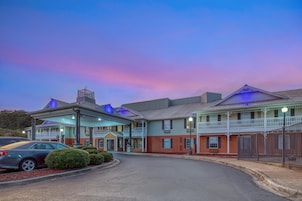 A hotel with a covered entrance, multiple stories, and a parking area.