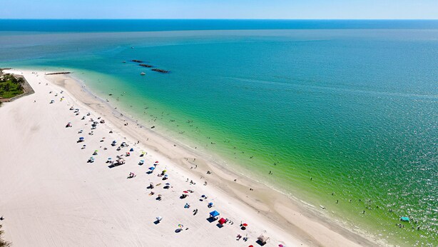 A beach with clear turquoise water, a sandy shore, and several umbrellas.