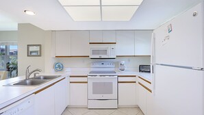 A modern kitchen with white cabinets, a built-in microwave, oven, and refrigerator.