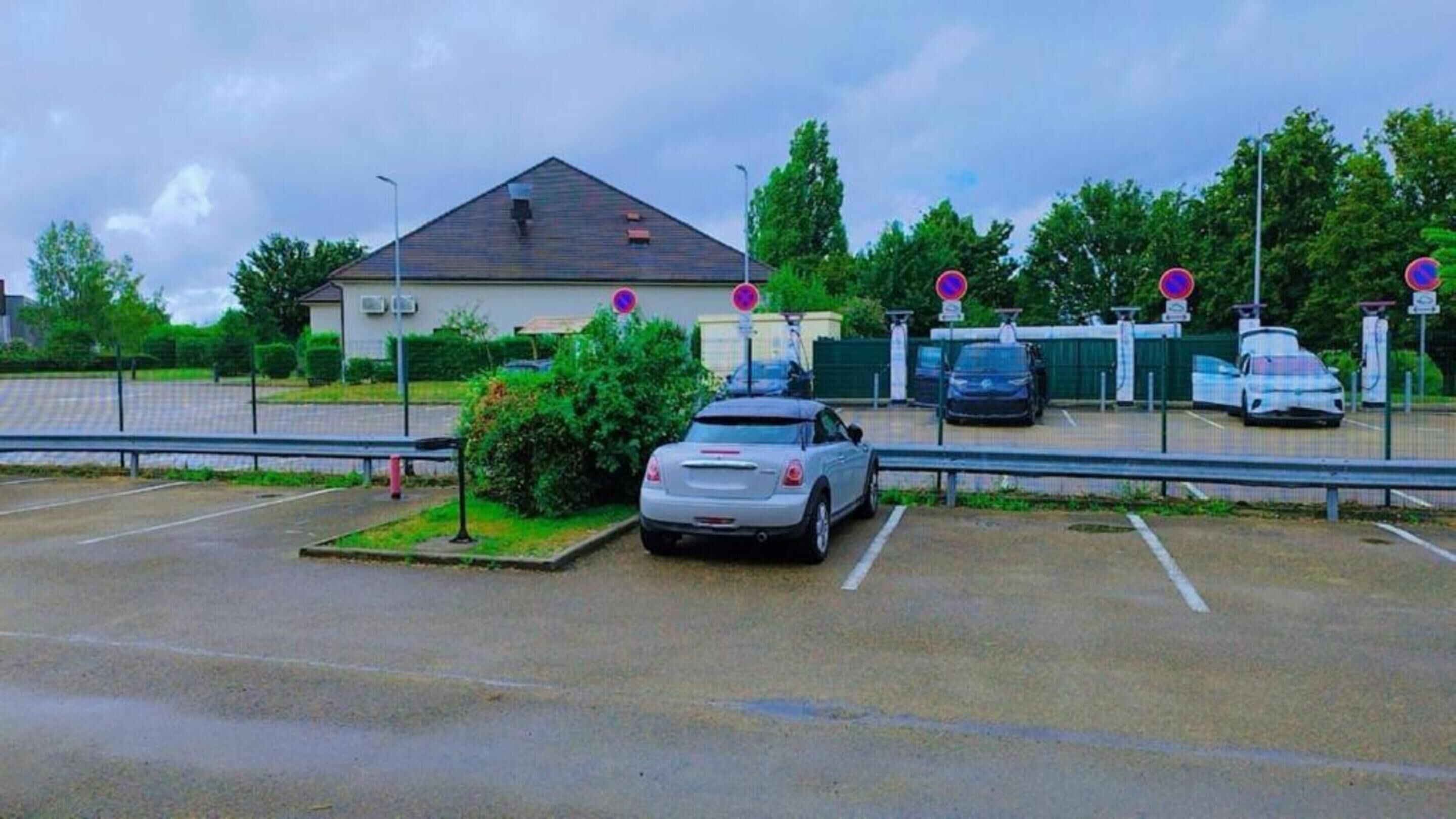 Un estacionamiento con coches y un edificio al fondo.