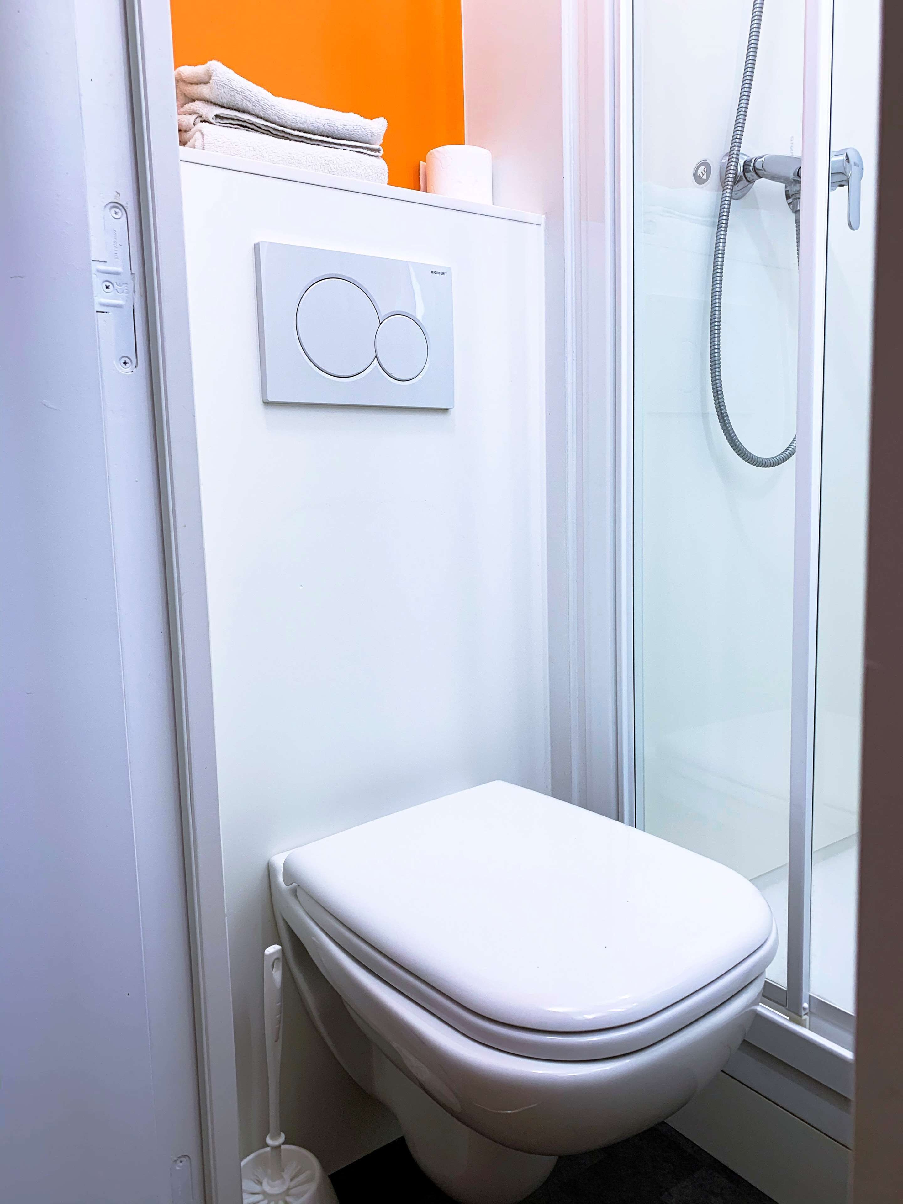 A bathroom with a toilet, a shower, and a towel rack.