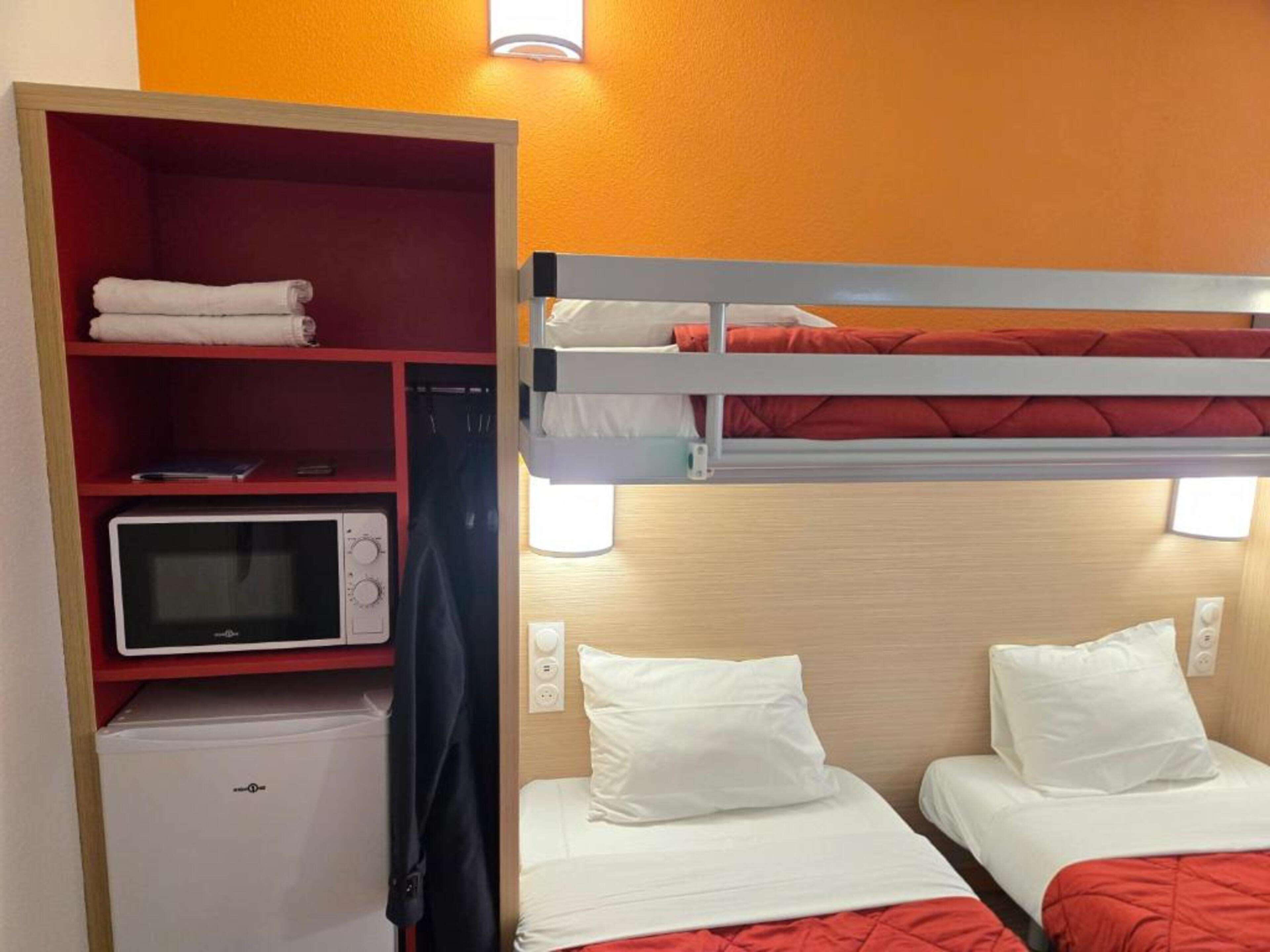 A compact hotel room with a bunk bed, a microwave, and a small refrigerator.