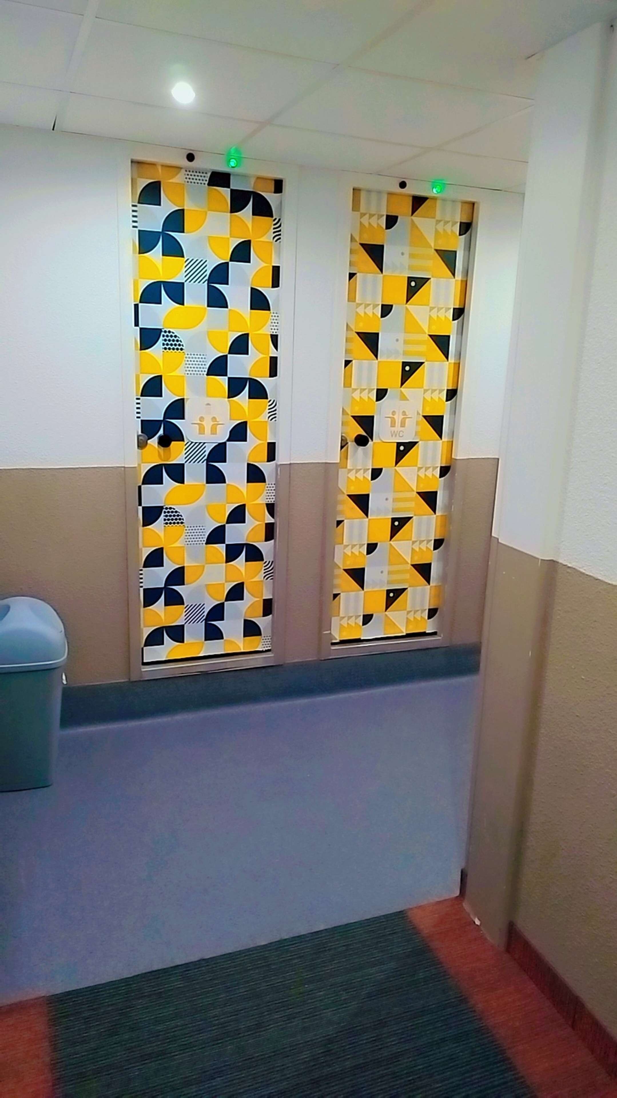 En hall med mönstrade väggar och en papperskorg.