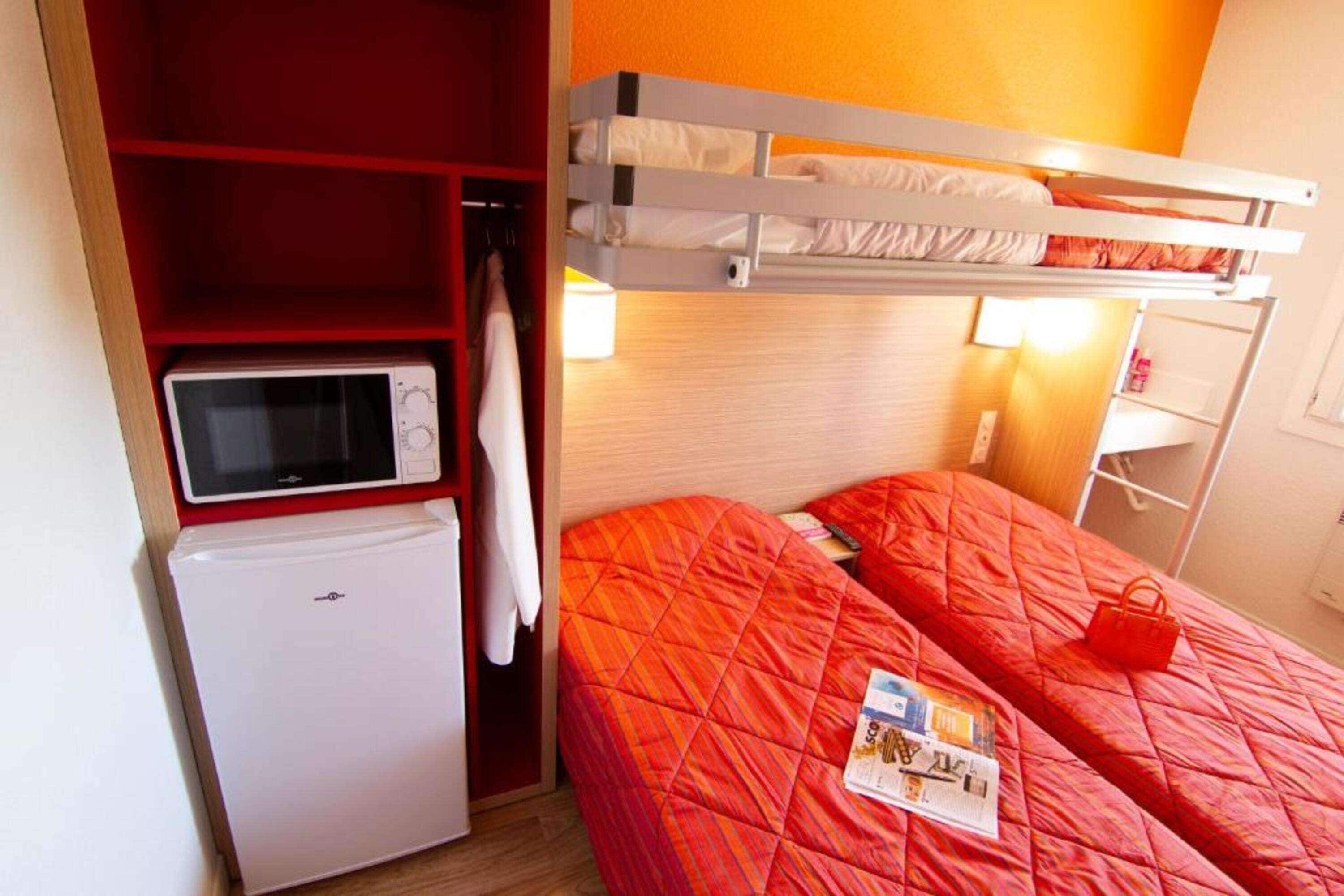 A compact hotel room with a bunk bed, a microwave, and a small refrigerator.