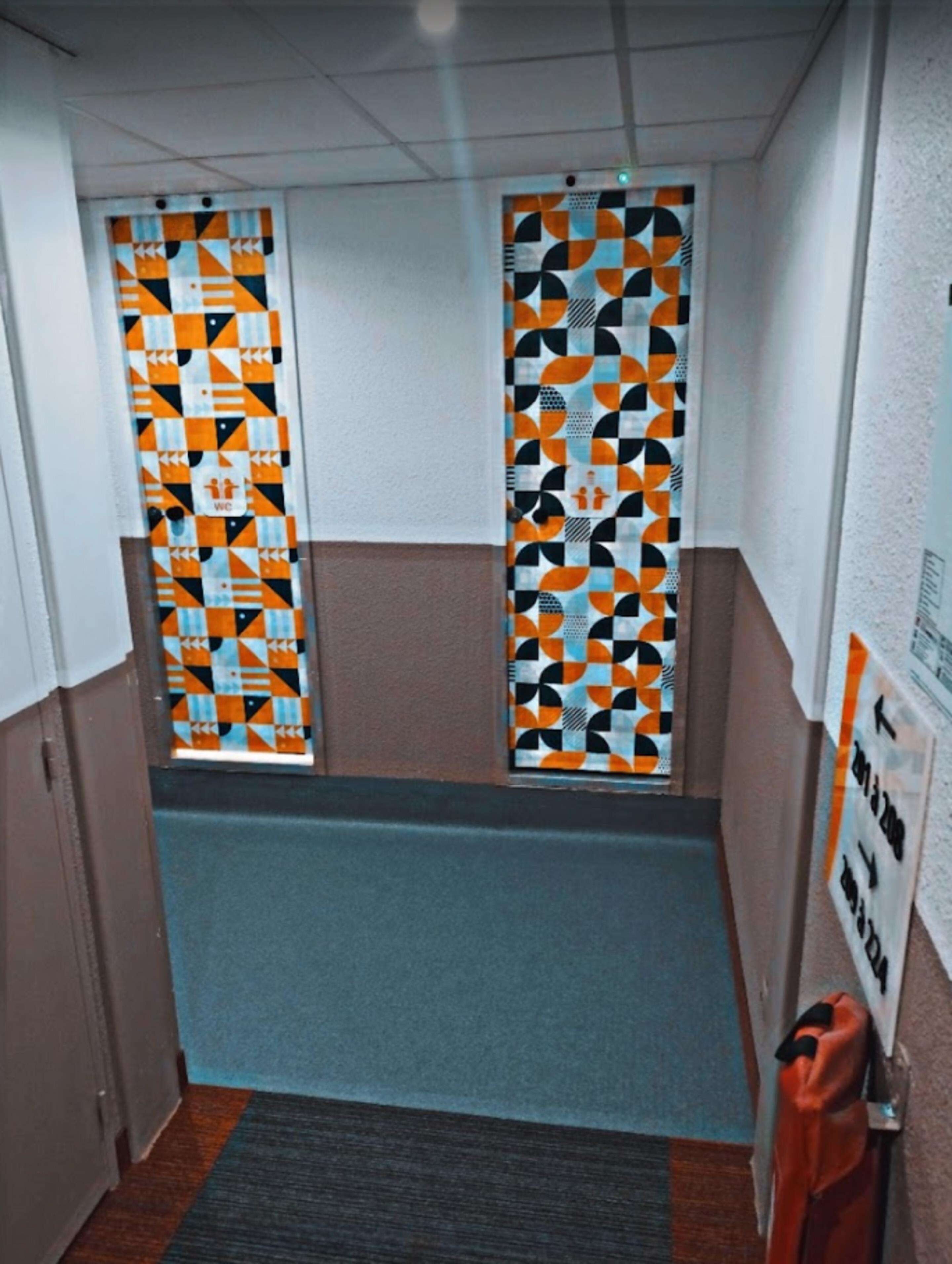 A narrow hallway with patterned glass doors and a blue carpet.