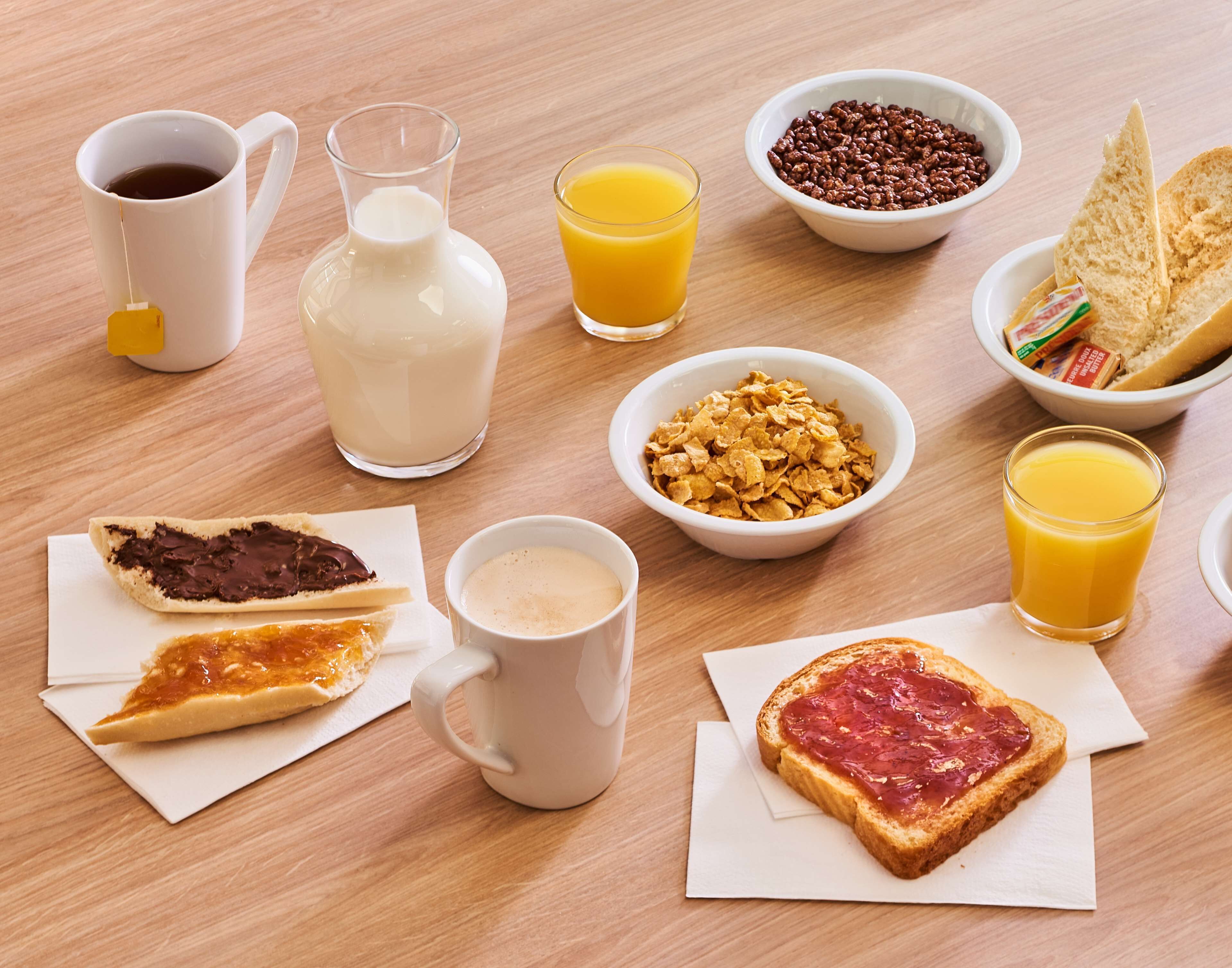 Een ontbijttafel met diverse etenswaren en drankjes.
