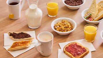 Een ontbijttafel met diverse etenswaren en drankjes.