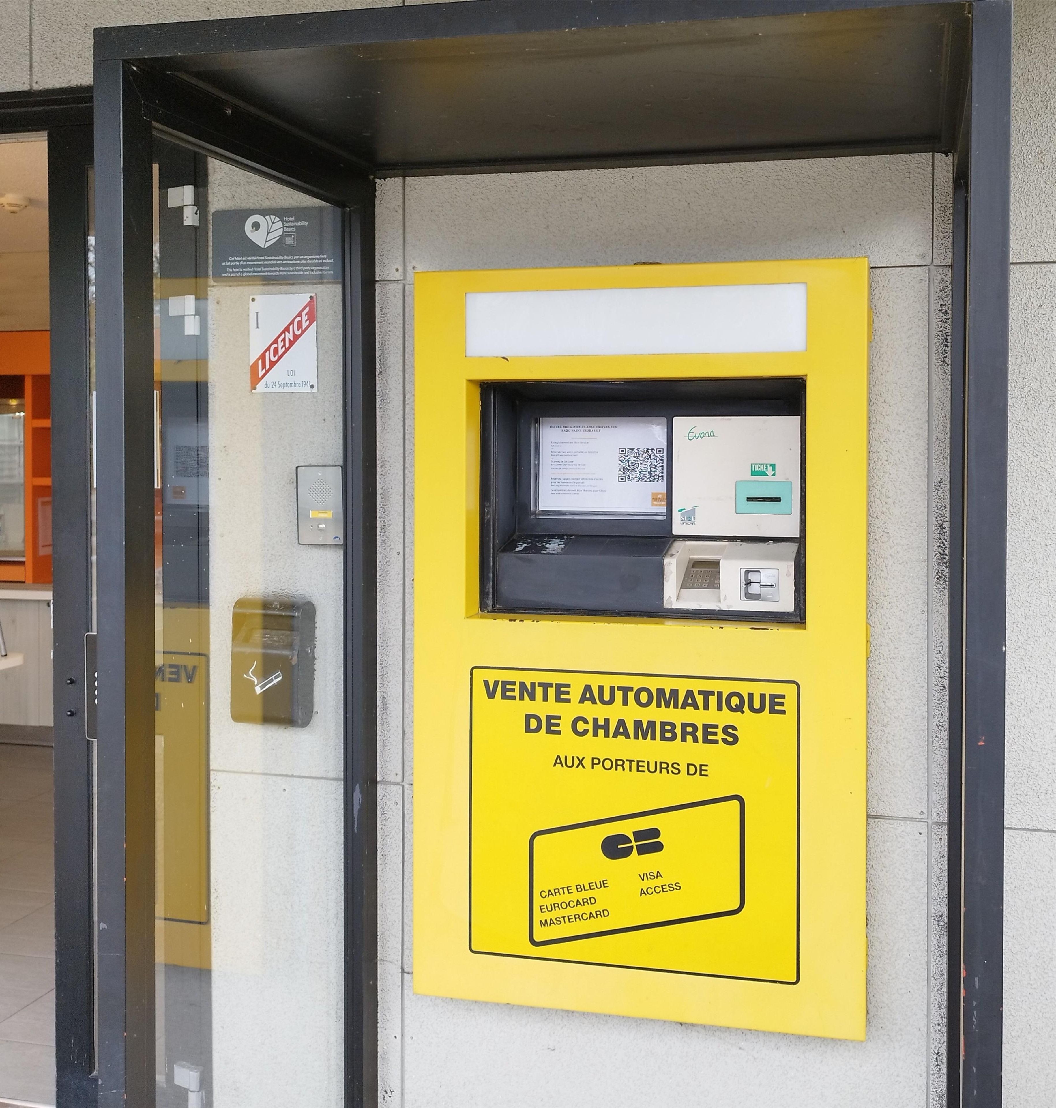 An ATM machine with a yellow sign indicating it is for automatic room sales.
