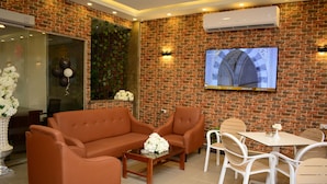 Un rincón interior acogedor con pared de ladrillo, televisor de pantalla plana y un arreglo floral.