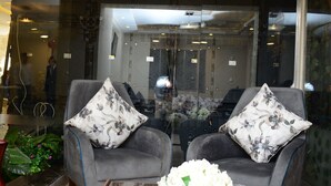 Un salón moderno con un sofá gris, dos cojines estampados y una mesa de centro de cristal con flores blancas.