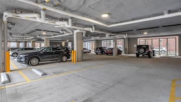 Eine mehrgeschossige Parkgarage mit Betonpfeilern, gelben Markierungen und mehreren parkenden Fahrzeugen.