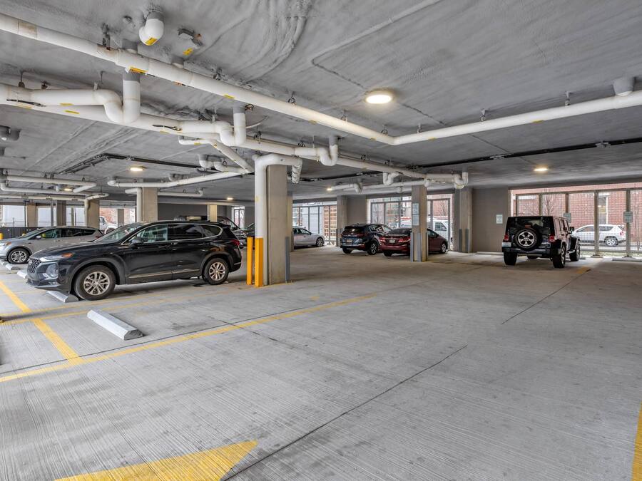 Eine mehrgeschossige Parkgarage mit Betonpfeilern, gelben Markierungen und mehreren parkenden Fahrzeugen.