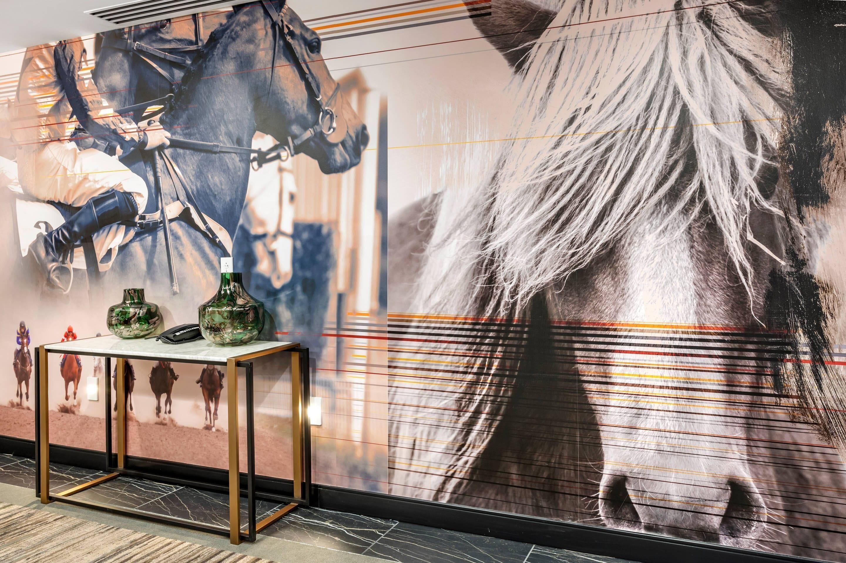 A wall with a large horse mural, a table with vases, and a phone.
