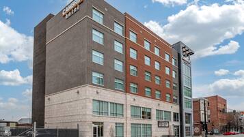 Un hotel de varios pisos con un diseño moderno, que presenta una combinación de fachadas de ladrillo y concreto, ventanas amplias y un letrero llamativo para el Cambridge Hotel.