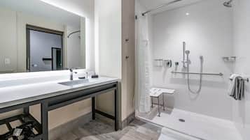 Un baño moderno con un espejo grande, un lavamanos blanco y una ducha a ras de suelo.