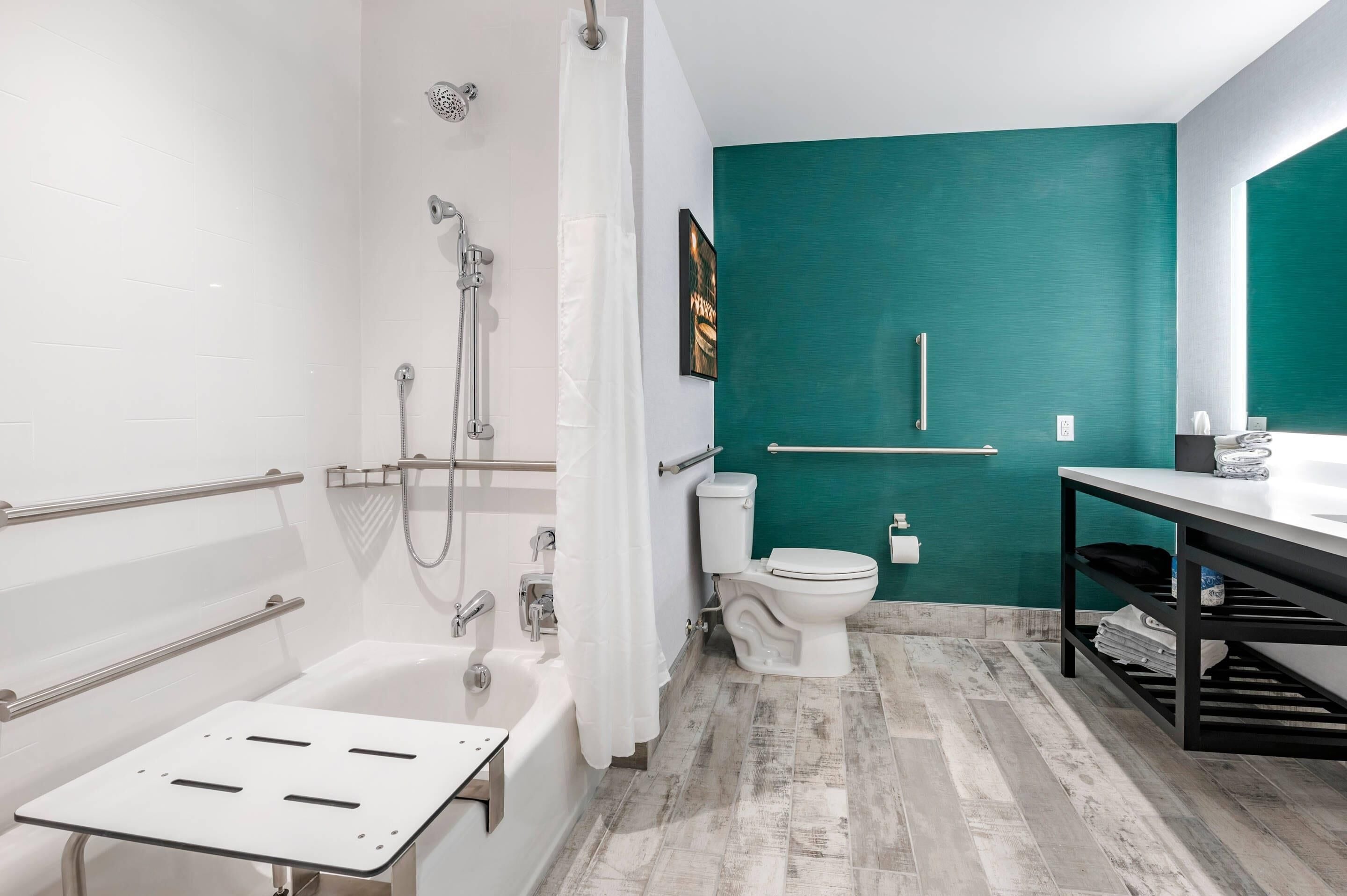 Un baño moderno con una bañera blanca, ducha, inodoro y tocador con lavabo.