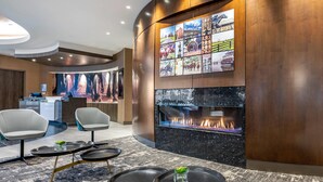 A modern lobby with a fireplace, seating area, and a reception desk. - Cambria Hotel Louisville Downtown-Whiskey Row (Louisville)