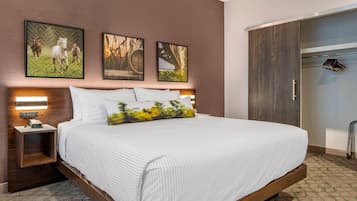 Habitación de hotel con una cama grande, cabecero de madera, mesita de noche con teléfono y armario con espejo.