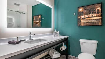 A modern bathroom with a large mirror, dual sinks, a toilet, and a towel rack.
