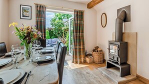 Ein Essbereich mit einem Holztisch, gedeckt für eine Mahlzeit, einer Couch und einem Kamin.