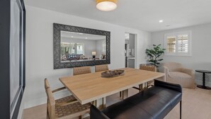 Un comedor moderno con una mesa de madera, sillas acolchadas, un banco y un espejo grande en la pared.