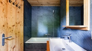 Une salle de bain avec une porte en bois, une baignoire, une douche et un lavabo.