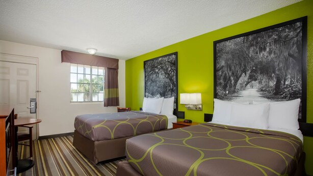 Habitació d'hotel amb dos llits, un escriptori i una finestra amb cortines.
