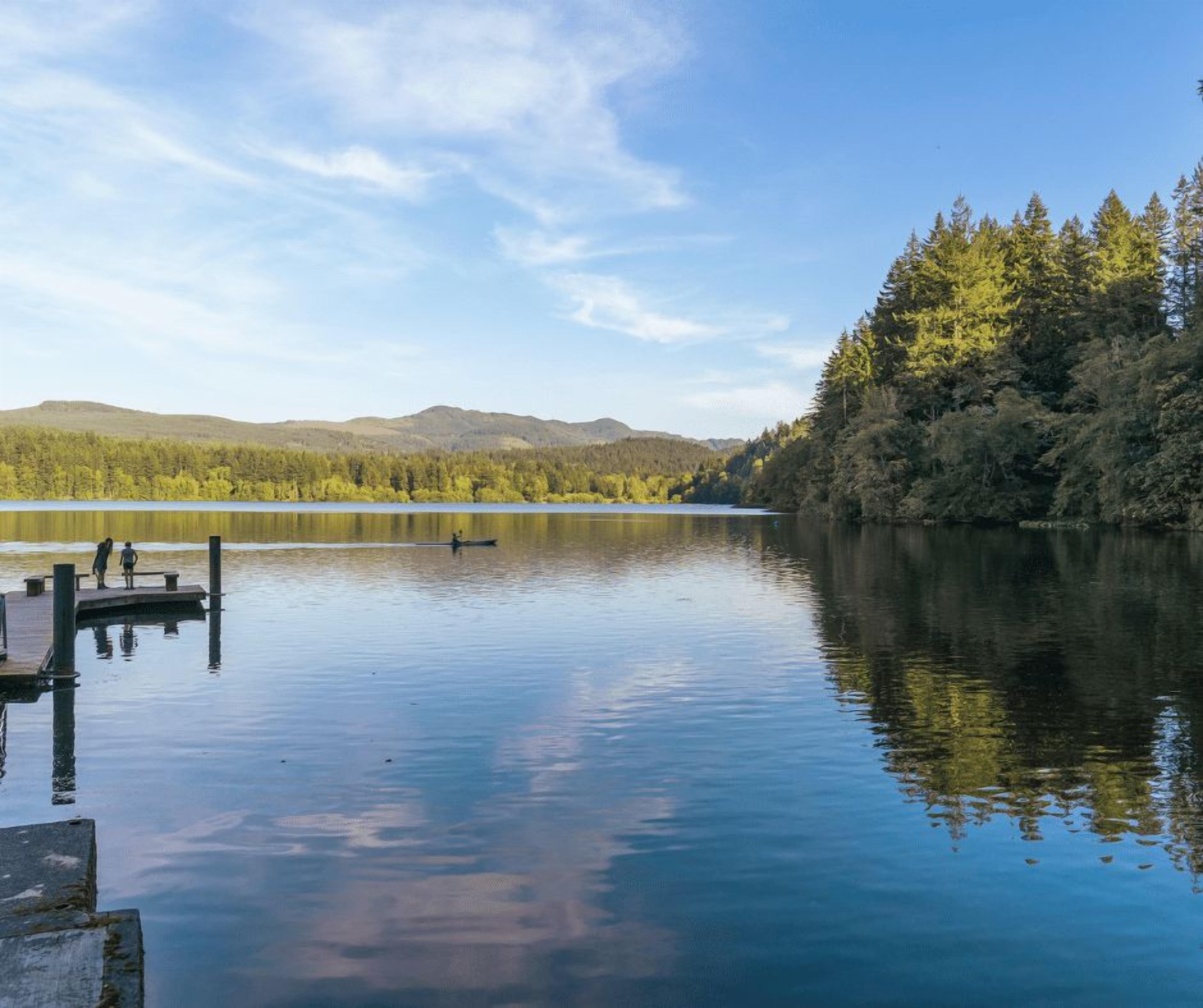 Un lac paisible, avec un quai et des arbres en arrière-plan.