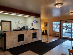A hotel reception area with a marble counter, a television, and a sign that reads "Belis Inn".