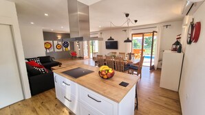 Eine moderne Küche mit einer zentralen Kochinsel, Holzschränken und einem Essbereich mit Tisch und Stühlen.