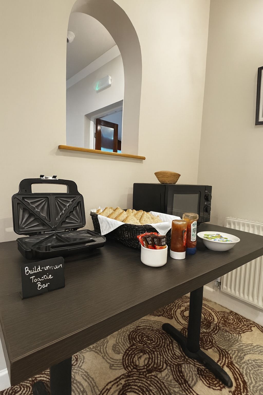 A kitchenette with a toaster, bread basket, coffee maker, and condiments.