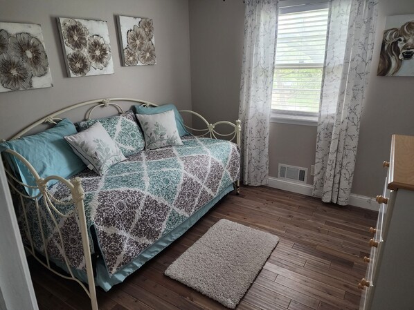Une chambre à coucher avec un lit en métal, une courtepointe à motifs et un petit tapis.